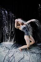 Girl dancer jumping and dancing in the white dust with flour on a black background. Studio shot of woman dancing with flour. photo