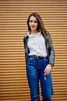 Portrait of stylish young girl wear on leather jacket and ripped jeans background shutter texture. Street fashion model style. photo