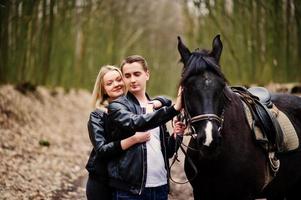 joven pareja elegante enamorada cerca de caballo en el bosque de otoño. foto