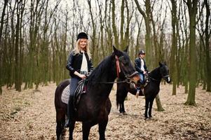 Young stylish couple riding on horses at autumn forest. photo