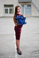 Young chubby teenage girl wear on red dress and jeans jacket posed against school backyard. photo