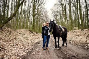 Young stylish couple in love near horse at autumn forest. photo