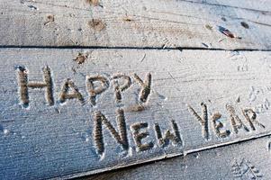 feliz año nuevo escrito sobre un fondo de madera con heladas foto