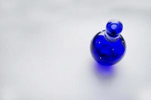 Blue glass pin like perfume on white background. photo