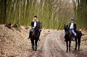 Young stylish couple riding on horses at autumn forest. photo