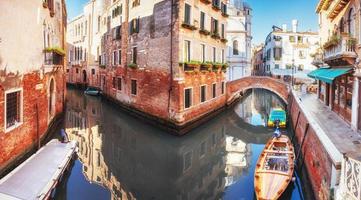 Traditional Gondolas on narrow canal between colorful historic houses in Venice Italy photo