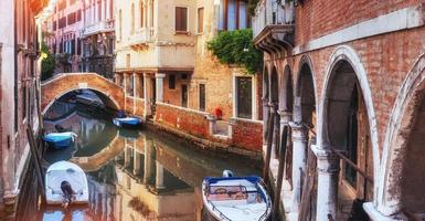 Traditional Gondolas on narrow canal between colorful historic houses in Venice Italy photo