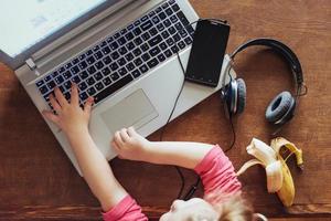 little girl presses the keyboard of his laptop photo