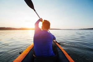 hombre flotando en el lago en un kayak al atardecer fantástico. foto