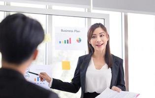 mujer de negocios haciendo una presentación frente a la junta, jóvenes empresarios reuniéndose y compartiendo ideas en la oficina foto