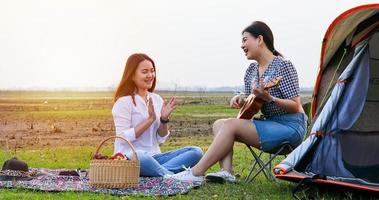 A group of Asian friends playing Ukelele and spending time making a picnic in the summer holidays.They are happy and have fun on holidays.