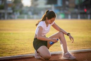 Asian Sports women using freezing spray for treating injured sportwomen's knee and leg  after run photo