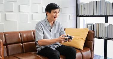 hombre asiático senior usando tableta y simulador de realidad virtual jugando juegos en la sala de estar y sintiéndose feliz. estilo de vida familia senior en el concepto de hogar. foto