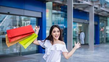 Beautiful asian young woman with shopping bags with smile while standing at the clothing store. Happiness, consumerism, sale and people concept photo