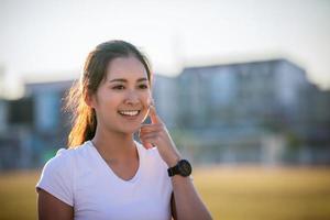 mujer asiática aplicando y rociando crema de protección solar en la piel antes de correr. deporte y concepto saludable foto