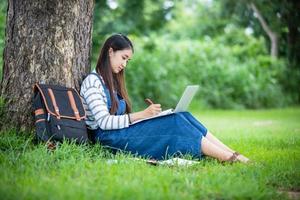 beautiful Asian girl student holding books and smiling at camera and learning and education concept  on park in summer for relax time photo