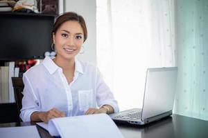 hermosas mujeres de negocios asiáticas revisando documentos y usando un cuaderno para trabajar en casa foto