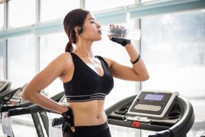 Sporty woman asia drinking water after exercises in the gym. Fitness - concept of healthy photo