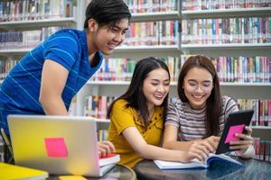 Group Asian  Students Smile and reading book and using notebook for helps to share ideas in the work and project. And also review the book before the exam photo