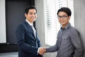 empresarios asiáticos dándose la mano y sonriendo su acuerdo para firmar el contrato y terminar una reunión foto