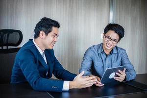 Hombres de negocios asiáticos y grupo que usan el cuaderno para socios comerciales que discuten documentos e ideas en reuniones y mujeres de negocios sonriendo felices por trabajar foto