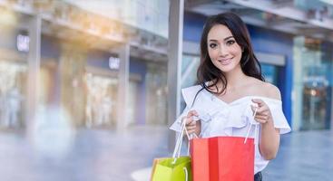 Beautiful asian young woman is standing holding shopping bags .She smile happiness in the shopping mall photo