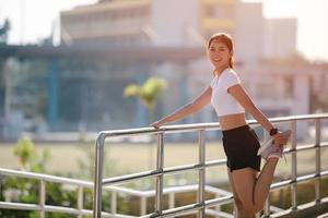 Mujeres sonrientes corredoras asiáticas haciendo ejercicio de estiramiento, preparándose para el entrenamiento matutino y el concepto de estilo de vida en la ciudad