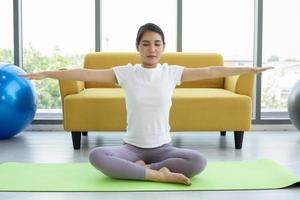 mujer asiática haciendo ejercicio de yoga en casa foto