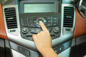 Asian Women press button on car radio for listening to music. photo