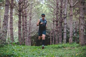 A man Runner of Trail and athlete's feet wearing sports shoes for trail running in the forest photo