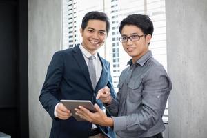 Hombres de negocios asiáticos y grupo que usan el cuaderno para socios comerciales que discuten documentos e ideas en reuniones y mujeres de negocios sonriendo felices por trabajar foto