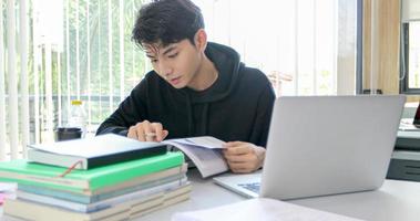 Asian men Students Smile and reading book and using notebook for helps to share ideas in the work and project. And also review the book before the exam photo