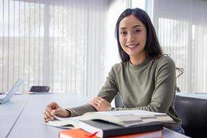 Asian women Students Smile and reading book and using notebook for helps to share ideas in the work and project. And also review the book before the exam photo