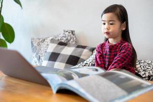 las niñas o hijas asiáticas usan cuadernos y tecnología para aprender en línea durante las vacaciones escolares y ver dibujos animados en casa. conceptos educativos y actividades de la familia foto
