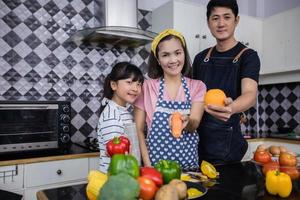 las familias asiáticas están cocinando y los padres están enseñando a sus hijas a cocinar en la cocina de casa. actividades familiares en vacaciones y felices en concepto de recreación foto