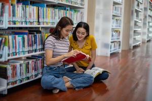 los estudiantes asiáticos del grupo sonríen y leen libros y usan un cuaderno para ayudar a compartir ideas en el trabajo y el proyecto. y también repasar el libro antes del examen foto