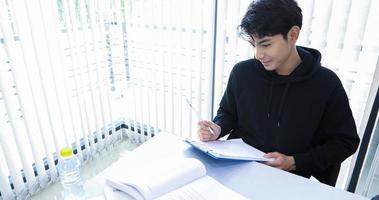 Asian men Students Smile and reading book and using notebook for helps to share ideas in the work and project. And also review the book before the exam photo