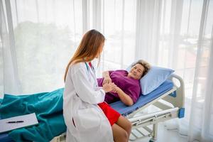 Doctor meeting and explaining medication to old woman patient lying in bed at Hospitals photo