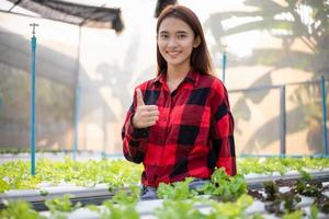 Smiling Asian woman farmer in greenhouse hydroponic organic.Small business entrepreneur and organic vegetable farm and healthy food concept photo