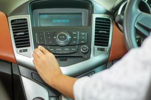 Asian Women press button on car radio for listening to music. photo