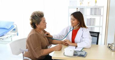 Doctor using stethoscope for examining old women patient in his at Hospitals photo