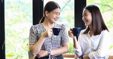 dos mujeres asiáticas bebiendo café y mujeres alegres cotilleando en un café foto