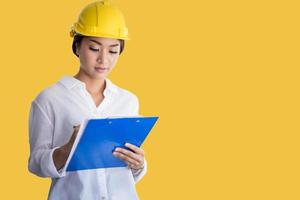 Asian women engineering inspecting and working and holding blueprints on yellow background photo