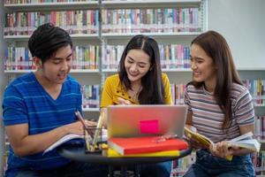 Group Asian  Students Smile and reading book and using notebook for helps to share ideas in the work and project. And also review the book before the exam photo