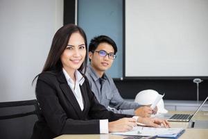 Hombres de negocios asiáticos y grupo que usan el cuaderno para socios comerciales que discuten documentos e ideas en reuniones y mujeres de negocios sonriendo felices por trabajar foto