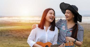 A group of Asian friends playing Ukelele and spending time making a picnic in the summer holidays.They are happy and have fun on holidays. photo