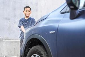 niño asiático cepillando los dientes con espuma saliendo de su boca foto