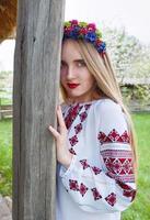Young beautiful blonde woman with long hair in Ukrainian blouse and in a wreath in outdoor ethnic village in Kyiv Ukraine photo