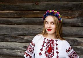 Young beautiful blonde woman with long hair in Ukrainian blouse and in a wreath in outdoor ethnic village in Kyiv Ukraine photo