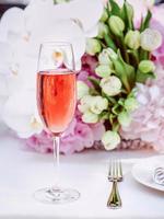 flowers and glass of rose sparkling outdoor, plate, fork, knife on the table. Cutlery, food, lunch, party concept photo